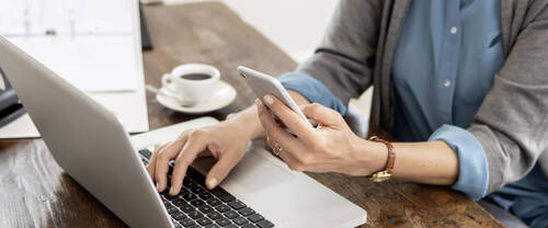 Personne étant sur son smartphone devant son ordinateur